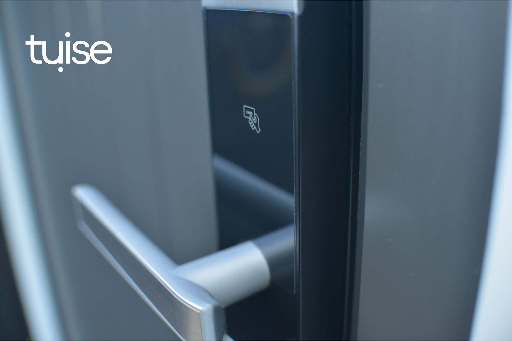 Close-up of a door handle with 'tuise' branding on a metallic surface.
